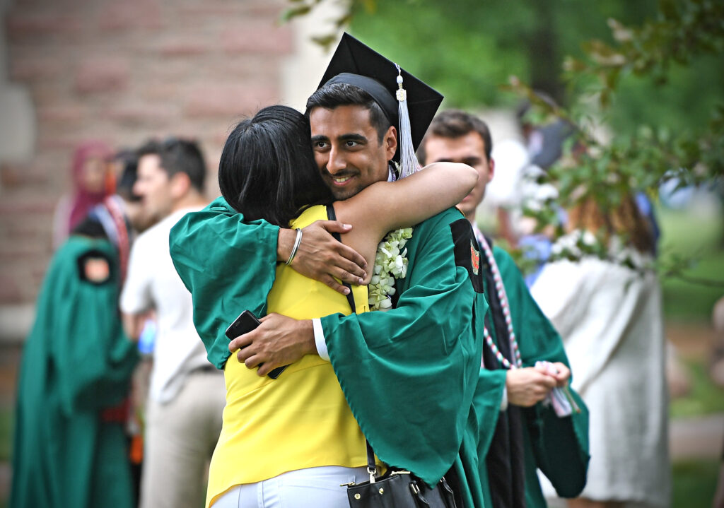 grad hugging family member during commencement