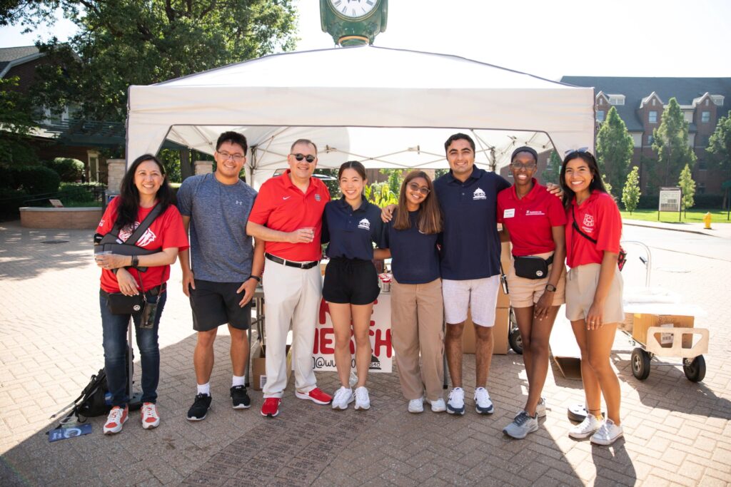 Dr. Anna Gonzalez and Chancellor Martin pose with undergraduate students and their families during orientation