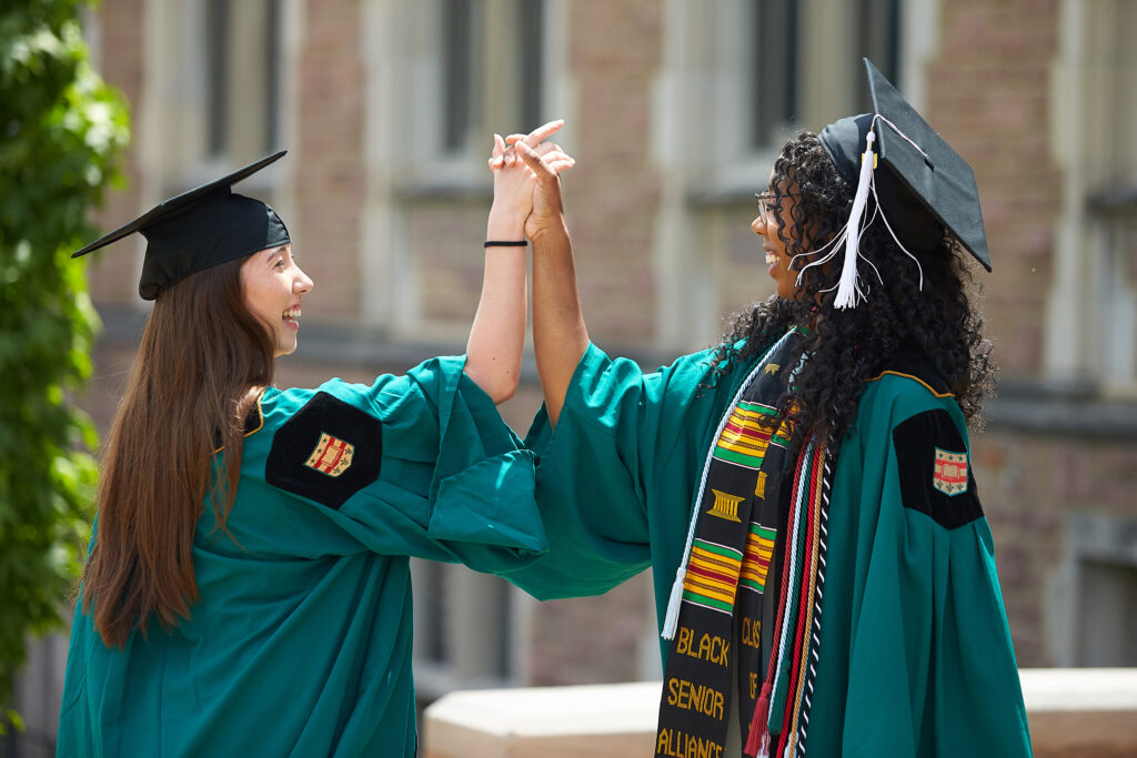 two grads shaking hands after commencement