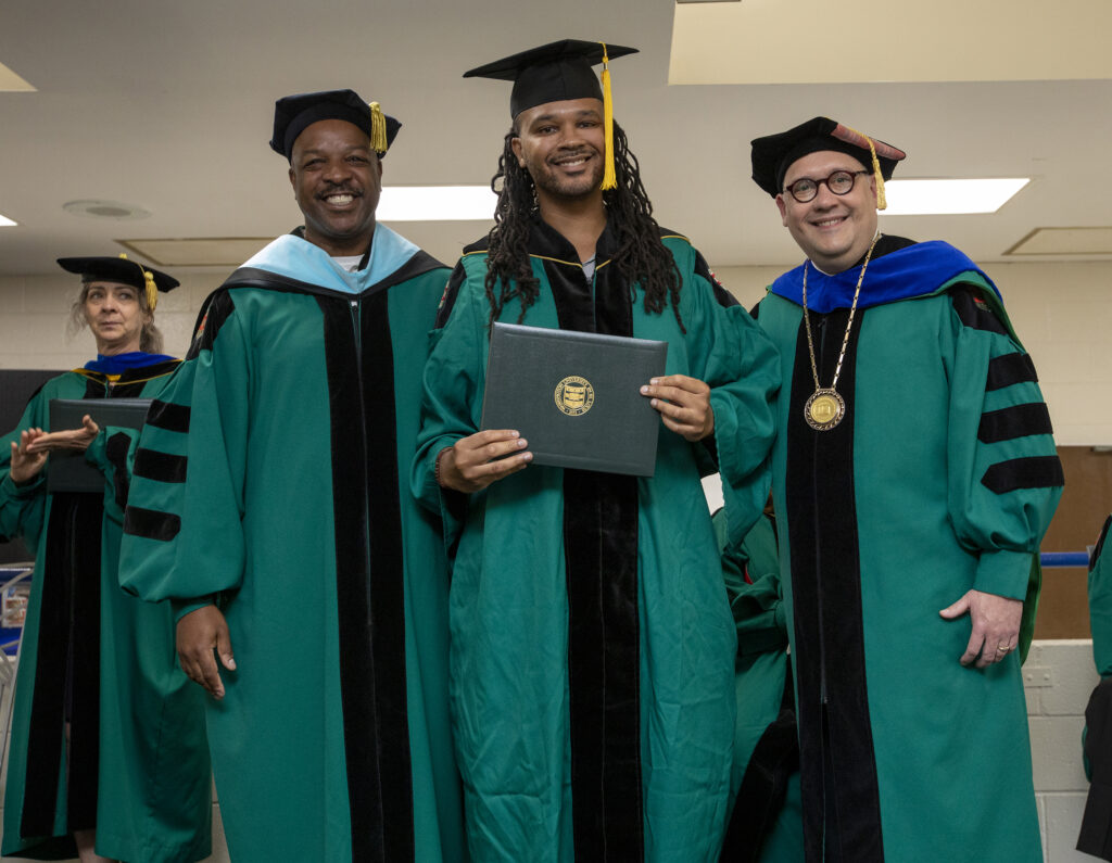 PEP graduate Larry Marshall receives his bachelor’s degree at PEP’s 2022 graduation ceremony, alongside Sean Armstrong, dean of University College, and Chancellor Andrew D. Martin