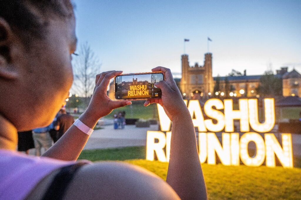 Image of phone taking a photo of lit-up WashU Reunion sign