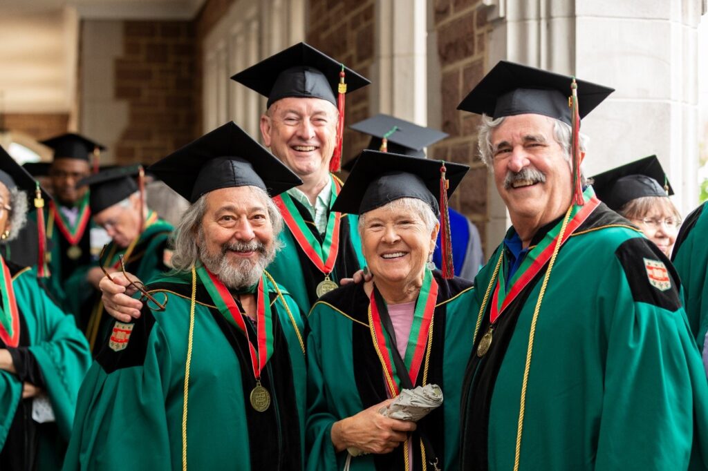 Group of five reunion celebrants in green regalia smiling