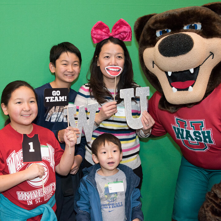 a mom and her three kids posing with WashU mascot at Eliot family event